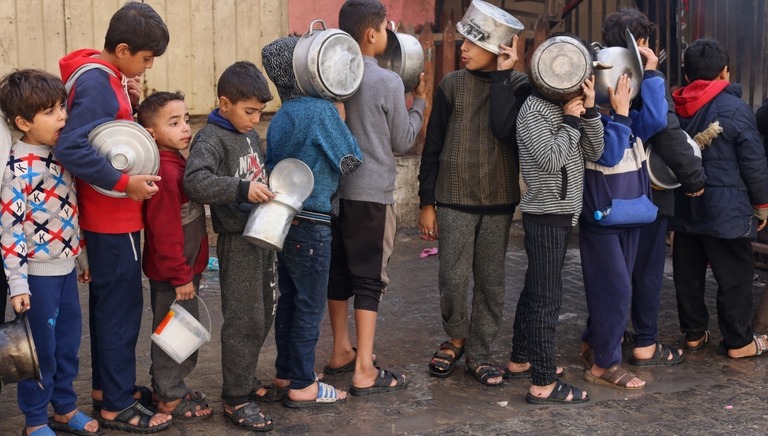 慈善団体の用意した食料を求め、鍋をもって列に並ぶパレスチナ人の子どもたち/Saleh Salem/Reuters