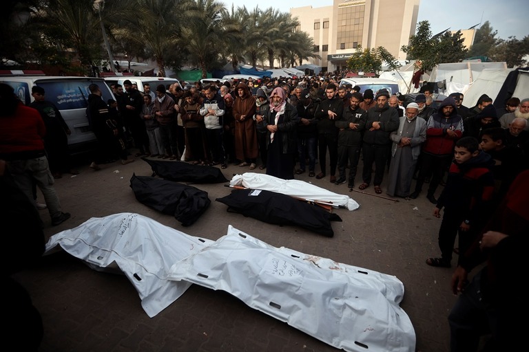 イスラエル軍の爆撃で死亡した人の遺体を前に遺族が祈りをささげる＝２０日、ガザ南部ハンユニス/Mohammed Dahman/AP