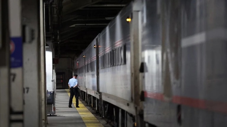 シカゴの鉄道駅でミルウォーキー行きのアムトラックの車両の横に佇む車掌/Scott Olson/Getty Images