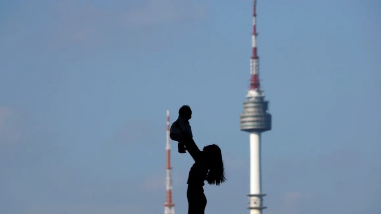 Ｎソウルタワーを背景に赤ちゃんを抱き上げる女性/Kim Hong-Ji/Reuters/File