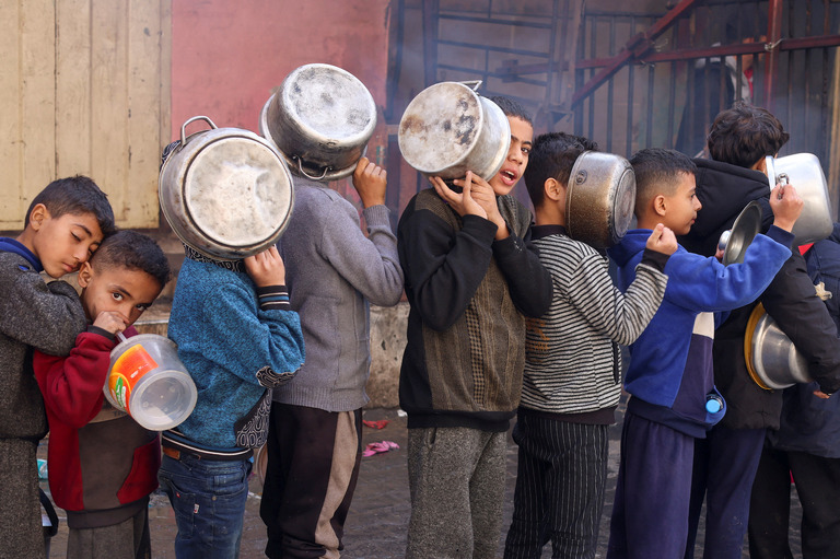 ガザ南部で鍋を手に炊き出しの列に並ぶパレスチナ人の子どもたち/Saleh Salem/Reuters/File