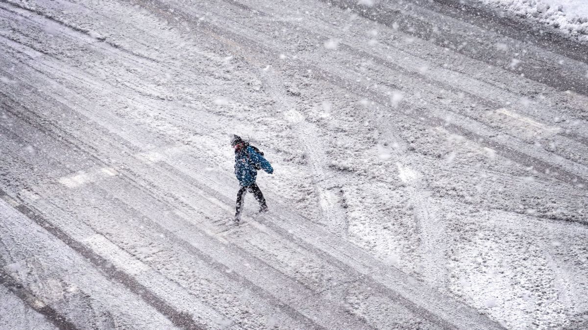 アイオワ州アイオワシティーで雪に覆われた通りを渡る人＝９日/Scott Olson/Getty Images