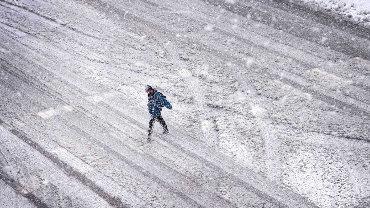 アイオワ州アイオワシティーで雪に覆われた通りを渡る人=9日/Scott Olson/Getty Images