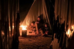 子どもと火にあたる男性＝１２月１８日、パレスチナ自治区ガザ地区ラファ