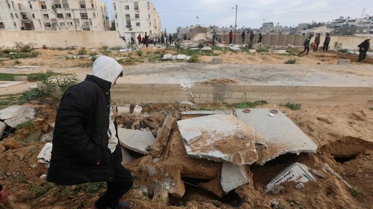イスラエル軍が捜索したハンユニスの墓地で、破壊された墓石を確認するパレスチナ人/Ahmed Zakot/Reuters