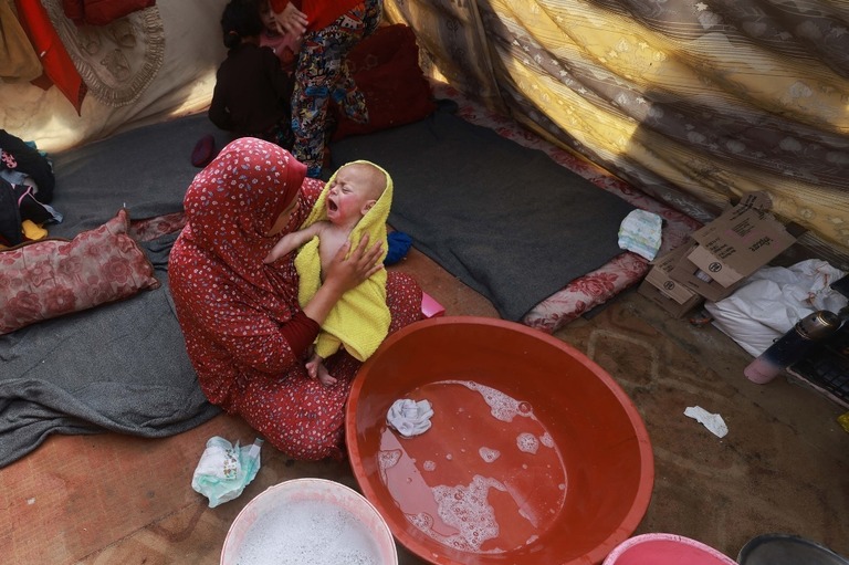 赤ちゃんをタオルで乾かす女性＝１８日、パレスチナ自治区ガザ地区南部ラファ/ AFP/Getty Images