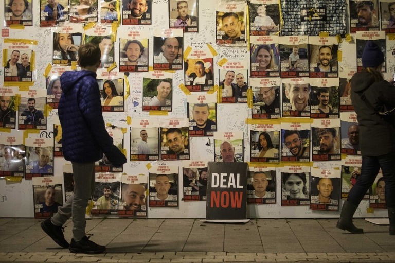 人質の写真が貼られている壁のそばを歩く人々/Amir Levy/Getty Images