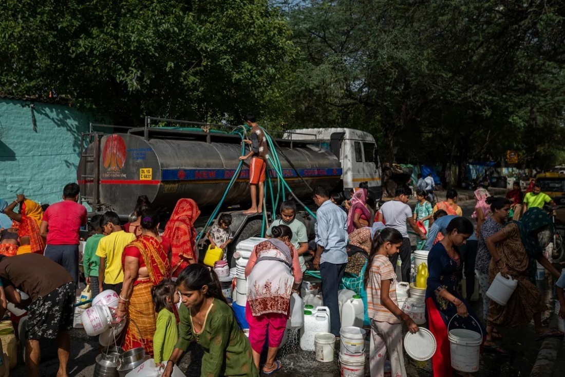スラム街で給水車から水を受け取る住民=2023年5月、インド・ニューデリー/Anindito Mukherjee/Bloomberg/Getty Images