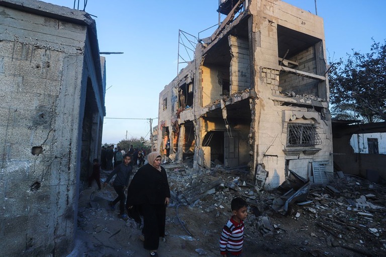 イスラエル軍の攻撃で破壊された住宅の脇を歩くパレスチナ人＝ラファ、１１日/Hatem Ali/AP