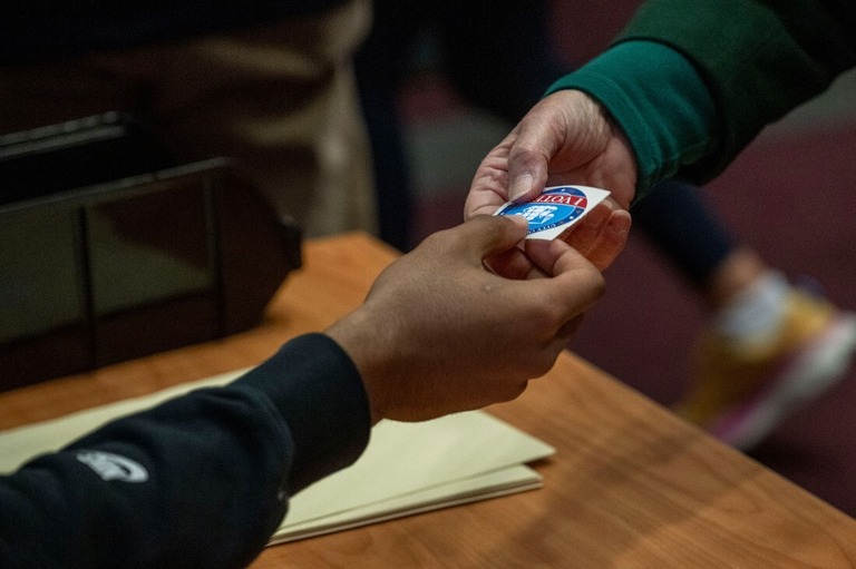 「投票済み」と書かれたステッカーを受け取る有権者＝５日、バージニア州アレクサンドリア/Kevin Wolf/AP