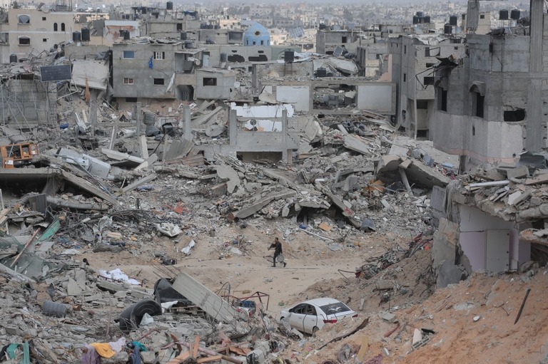 瓦礫の間を縫って歩く人＝ガザ地区南部ハンユニス/AFP via Getty Images