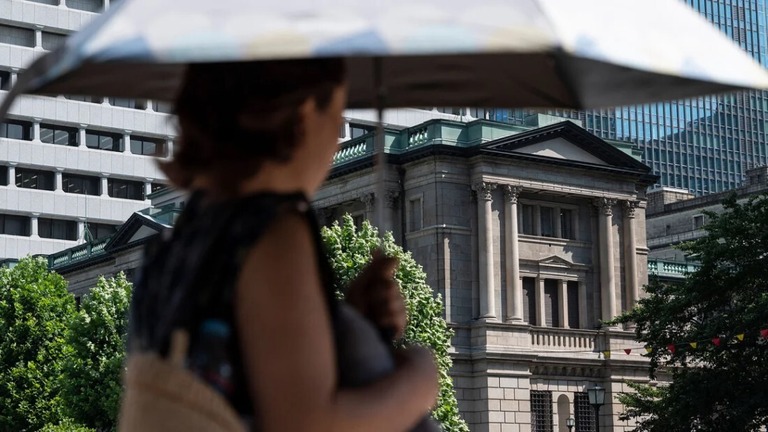 日銀の建物の横を通り過ぎる女性/Richard A. Brooks/AFP/Getty Images