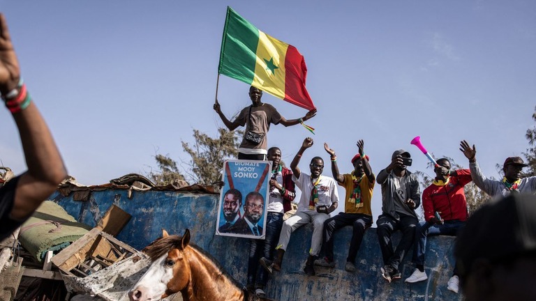 選挙期間中、セネガル国旗を持って反既得権益層を掲げる候補者の連合を支持する人々/John Wessels/AFP/Getty Images