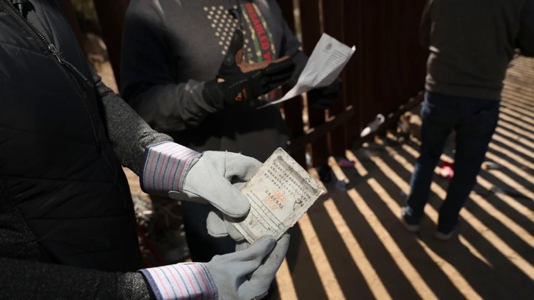 米加州のメキシコとの国境で見つかった中国のパスポートを手にする獣医のボランティア/Sandy Huffaker/Getty Images/File