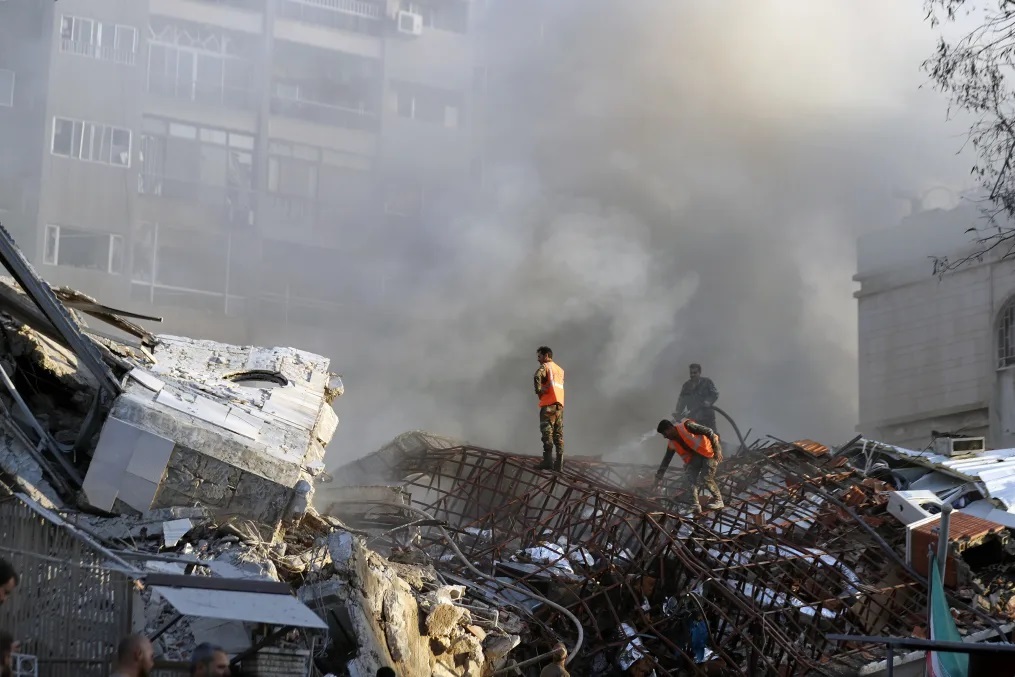 損壊した建物の残骸の上で作業する緊急要員/ Omar Sanadiki/AP