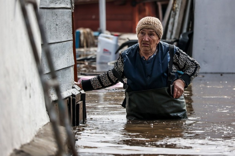 浸水した自宅付近を歩く女性＝１０日、ロシア・オレンブルク州
/AP