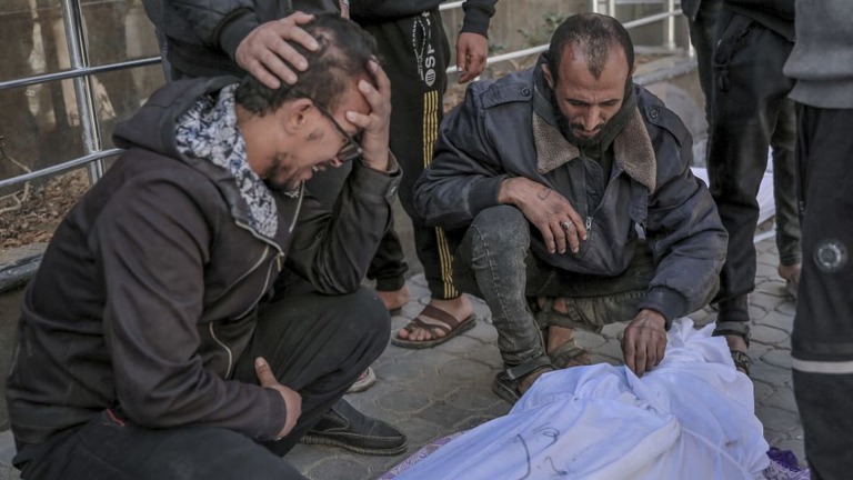 シファ病院の外で犠牲者を悼む人々/AFP/Getty Images