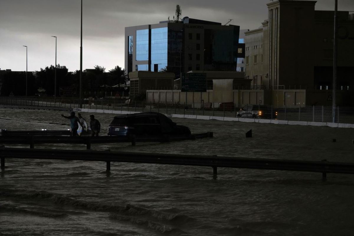 冠水した道路で車両をけん引しようとする人たち=16日、 アラブ首長国連邦(UAE)ドバイ/Jon Gambrell/AP