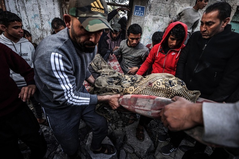 イスラエル軍からの攻撃により死亡した女性の遺体を運ぶパレスチナの人々＝２月１２日、パレスチナ自治区ガザ地区/Ali Jadallah/Anadolu/Getty Images