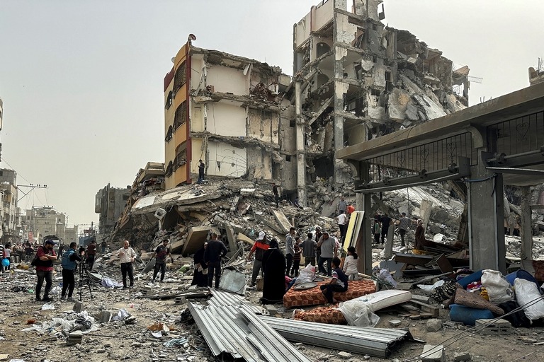 イスラエル軍による攻撃で破壊された建物の周りに集まるパレスチナ人たち/Doaa Rouqa/Reuters