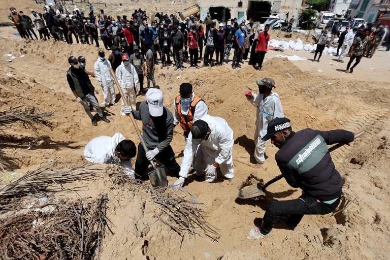 埋められた遺体を掘り起こす人々＝２１日、パレスチナ自治区ガザ地区ハンユニス/Ramadan Abed/Reuters
