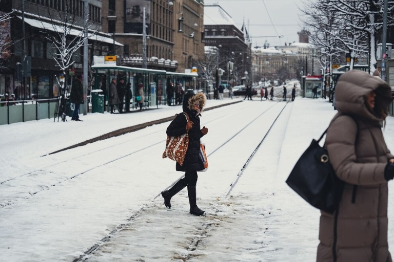 路面電車が運行停止となり雪に覆われた鉄道を渡る人々＝２３日、フィンランド・ヘルシンキ/Alessandro Rampazzo/Anadolu Agency/Getty Images 