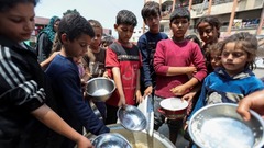 支援団体からの食事を受け取るパレスチナの子どもたち＝１日、パレスチナ自治区ガザ地区中部デイルアルバラ