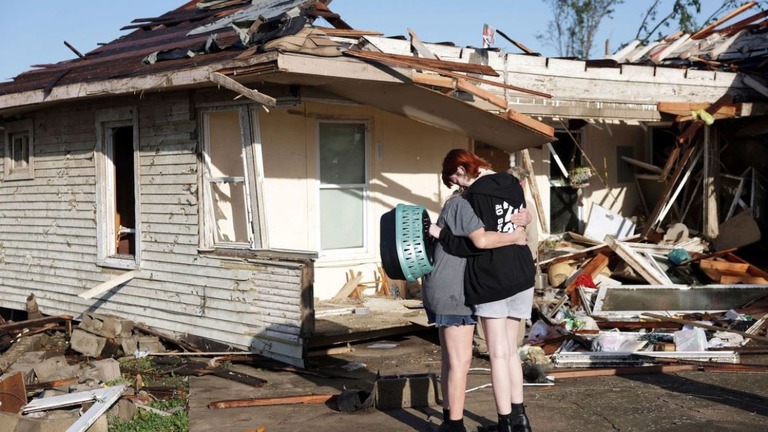 竜巻によって破壊された建物の外で抱き合う祖母と孫娘＝米オクラホマ州バーンズドール/Mike Simons/Tulsa World/AP