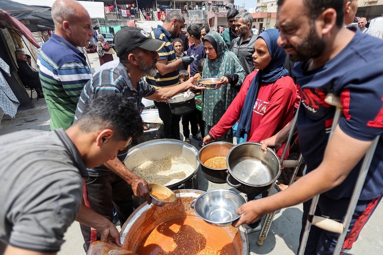 ガザ中部デイルアルバラでＷＣＫの提供する食事を受け取るパレスチナ人たち/Ramadan Abed/Reuters