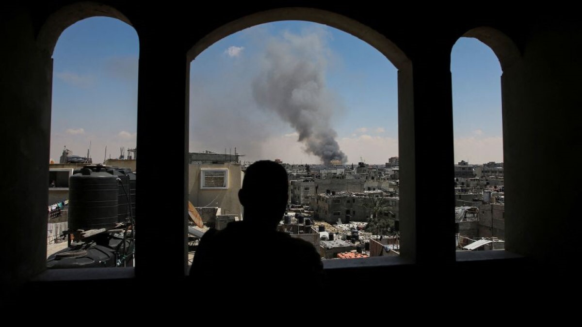 パレスチナ人が立ち上る煙を眺める様子/Hatem Khaled/Reuters