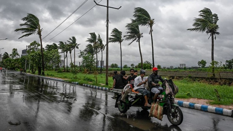 曇り空の下、移動する人々＝２６日、インド・コルカタ/Dibyangshu Sarkar/AFP/Getty Images
