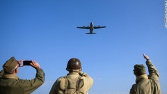 レプリカの服に身を包んだ熱心な人々がＣ１３０輸送機に反応する様子＝６日