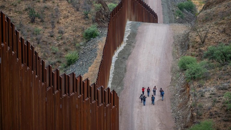中南米から違法に米国入りし、アリゾナ州の国境の壁付近を歩く移民ら/Brandon Bell/Getty Images