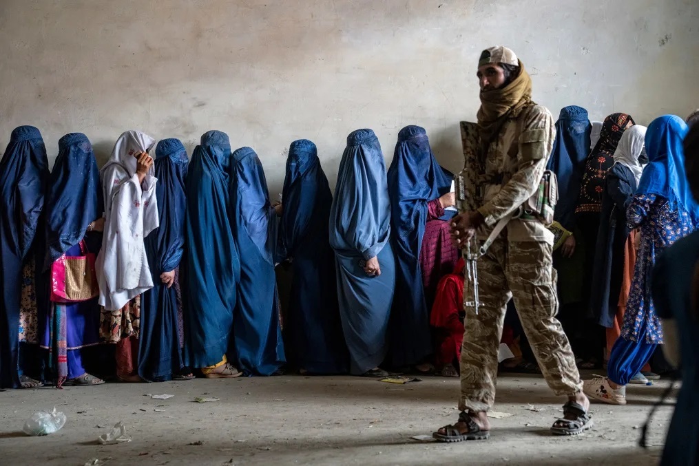 タリバンの兵士が警護する中、食料の配給に並ぶ女性たち=カブール/Ebrahim Noroozi/AP/File