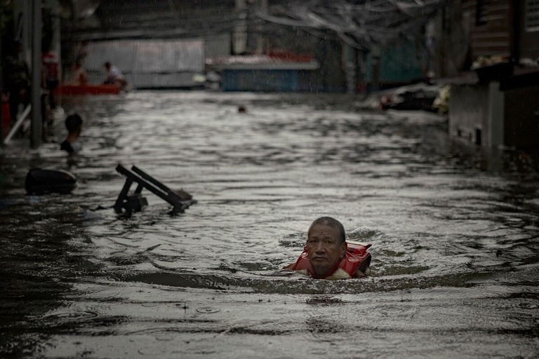 洪水の中を歩く住民＝２４日、フィリピン・マニラ首都圏ケソン市/Ezra Acayan/Getty Images