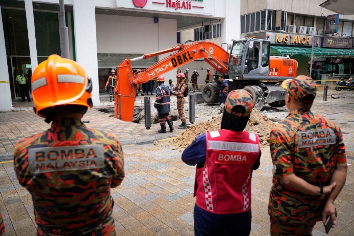 穴に落ちた女性の捜索活動にあたる係官=8月23日、マレーシア首都クアラルンプール/ Vincent Thian/AP