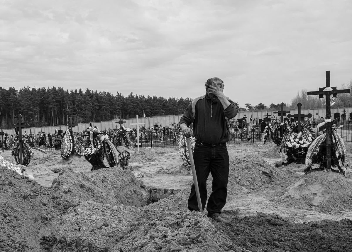 2022年4月、ロシア軍が撤退したブチャで新たに到着する遺体のための穴を掘る墓掘り作業者/Byron Smith