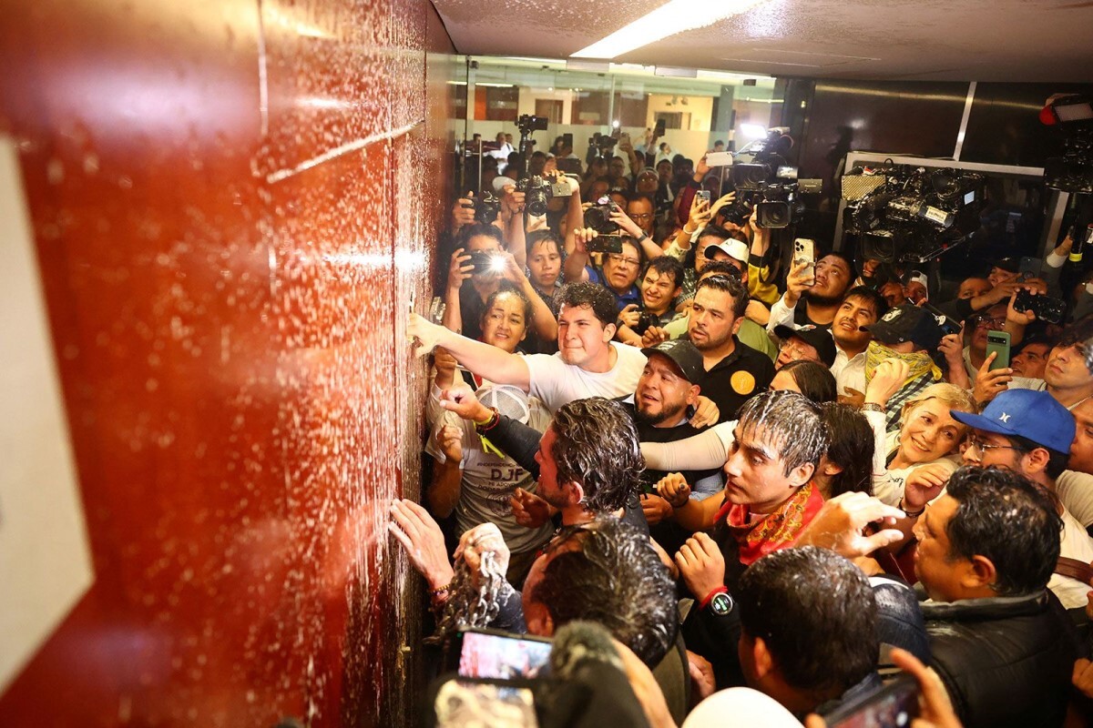 上院議事堂内のドアを破壊しようとするデモ参加者=10日、メキシコ/Raquel Cunha/Reuters
