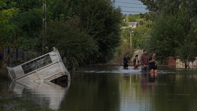冠水した道路を歩く人たち＝１５日、ルーマニア・ガラツィ/Andreea Campeanu/Reuters