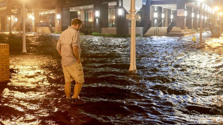 ミルトンがもたらした豪雨で冠水したフロリダ州フォート・マイヤーズの街路を歩く男性/Joe Raedle/Getty Images
