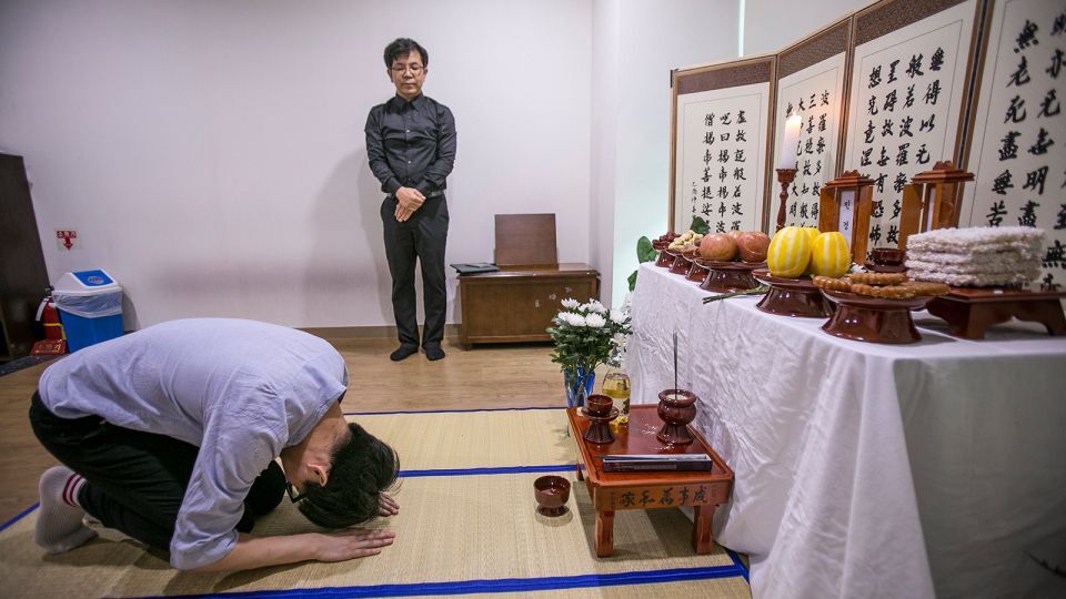 自宅と病院で身寄りなく息を引き取った2人の霊前で頭を下げる慈善団体のボランティア/Jean Chung/Getty Images