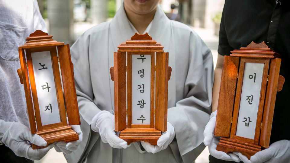 死亡した3人の位牌を手にする尼僧と慈善団体のスタッフ/Jean Chung/Getty Images