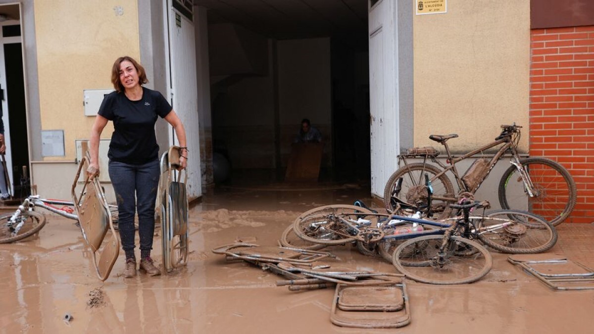 洪水により泥で覆われた椅子を運ぶ女性=スペイン・バレンシア州/Eva Manez/Reuters