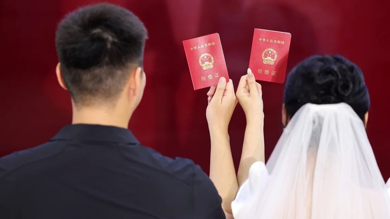 臨沂市の婚姻登録所で写真撮影のポーズを取る新婚カップル/Wang Yanbing/VCG/Getty Images
