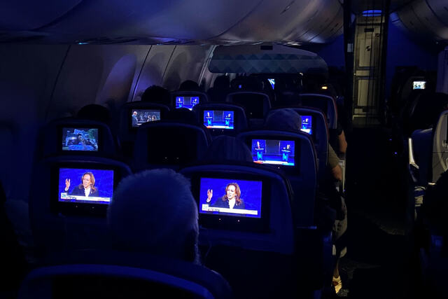 フライトの機内でトランプ氏とハリス氏の討論会を視聴する人々/Christine Rogers/CNN