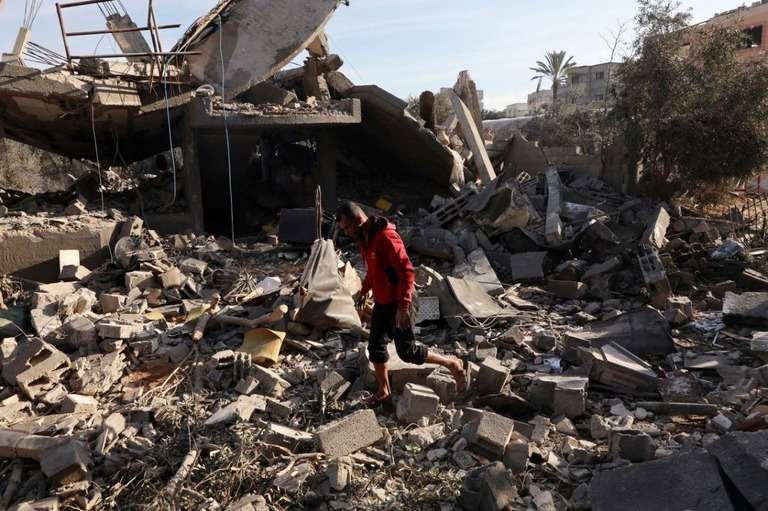 イスラエルの空爆を受けたガザ中部ヌセイラトの被害状況を調べるパレスチナ人の男性/Abd Elhkeem Khaled/Reuters
