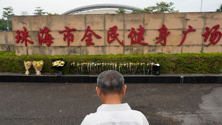 事件が起きたスポーツ施設前で手を合わせる男性=２０２４年１１月１３日、中国広東省珠海市/Ng Han Guan/AP