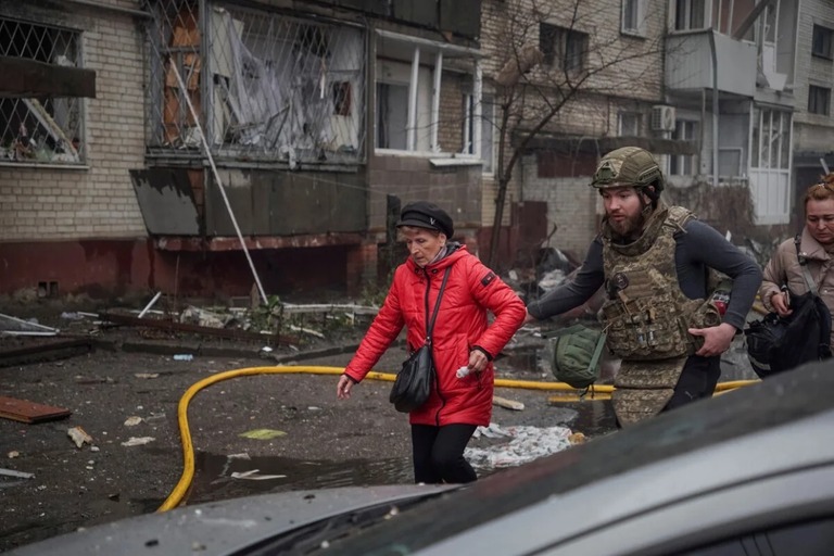 ウクライナの要員がロシアのミサイル攻撃を受けた集合住宅から女性を退避させる様子/Reuters