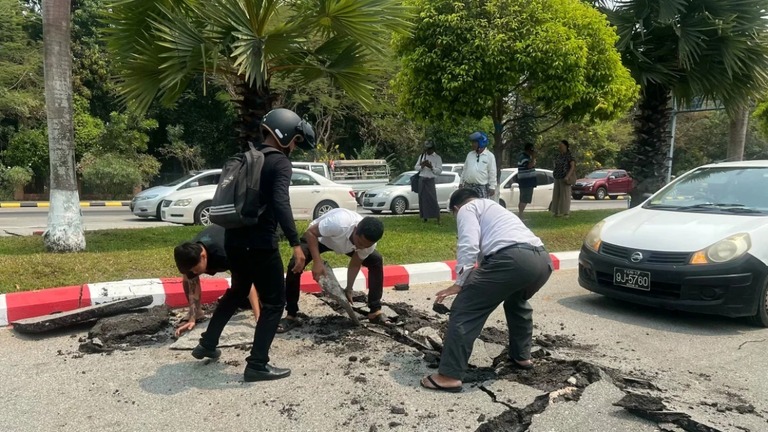 ミャンマー中部で発生した地震の後、損壊した道路のがれきを拾う人々＝２８日、首都ネピドー/AFP/Getty Images