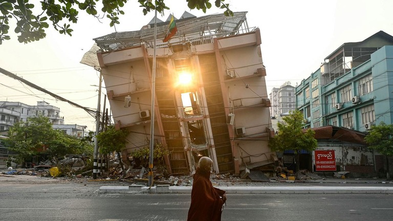 Ｍ７．７の地震から数日後、損壊した建物の前を歩く仏教徒/Sai Aung Main/AFP/Getty Images
